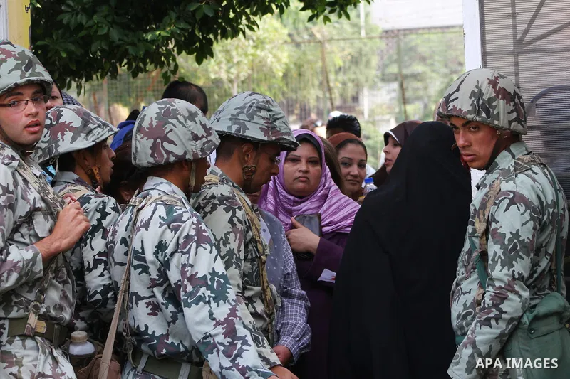 Egyptian soldiers stand guard as voters queue outside a school turned polling station in Cairo on November 28, 2011. Egyptians began voting in the first elections since the fall of autocrat Hosni Mubarak who was ousted i...