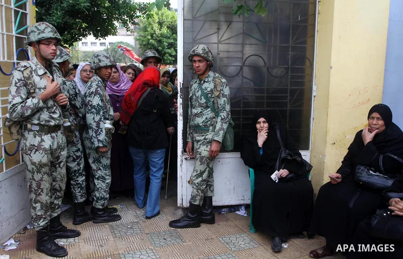 Egyptian soldiers stand guard as voters queue outside a school turned polling station in Cairo on November 28, 2011. Egyptians began voting in the first elections since the fall of autocrat Hosni Mubarak who was ousted i...