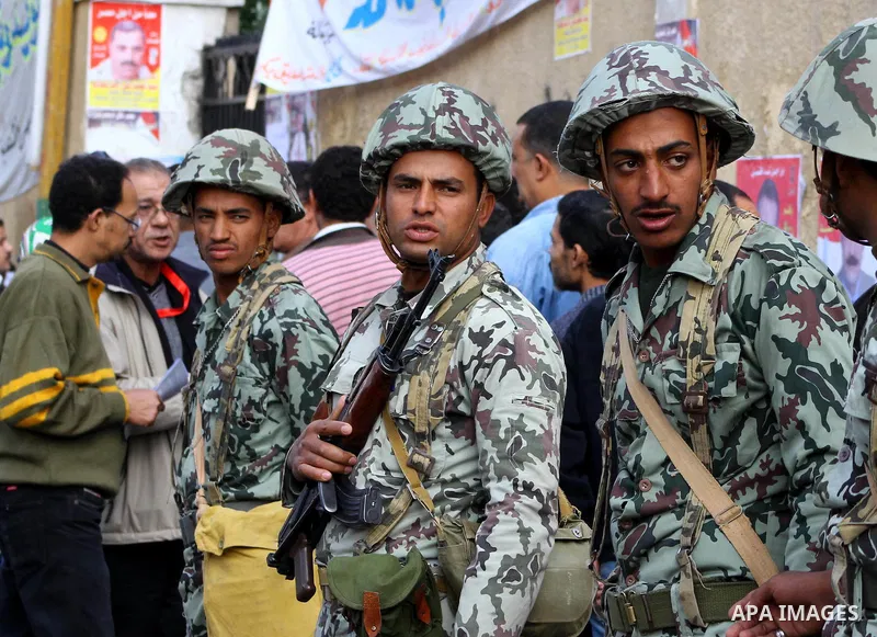 Egyptian soldiers stand guard as voters queue outside a school turned polling station in Cairo on November 28, 2011. Egyptians began voting in the first elections since the fall of autocrat Hosni Mubarak who was ousted i...