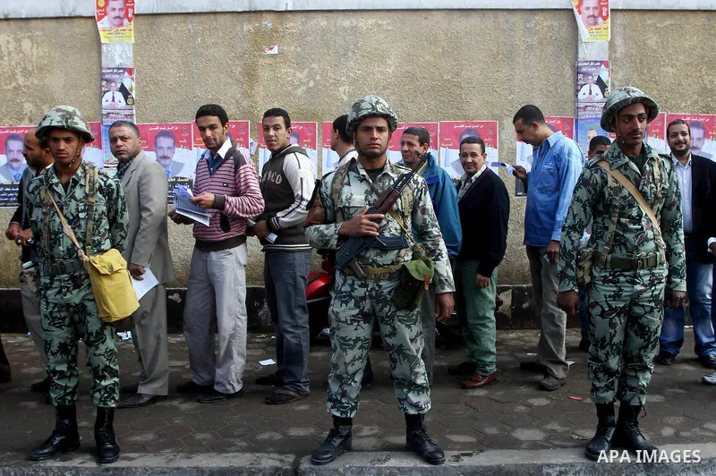 Egyptian soldiers stand guard as voters queue outside a school turned polling station in Cairo on November 28, 2011. Egyptians began voting in the first elections since the fall of autocrat Hosni Mubarak who was ousted i...