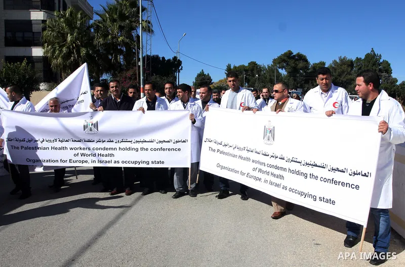 Palestinian doctors hold posters during a protest in front of UN headquarters in Ramallah, West Bank, November 28, 2011 to condemn holding the conference of World Health Organization for Europe, in Israel as the occupyin...