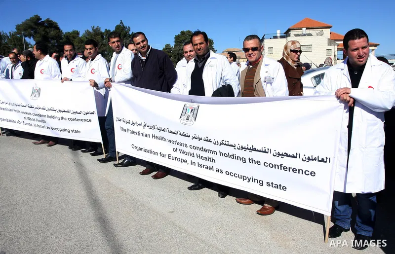 Palestinian doctors hold posters during a protest in front of UN headquarters in Ramallah, West Bank, November 28, 2011 to condemn holding the conference of World Health Organization for Europe, in Israel as the occupyin...