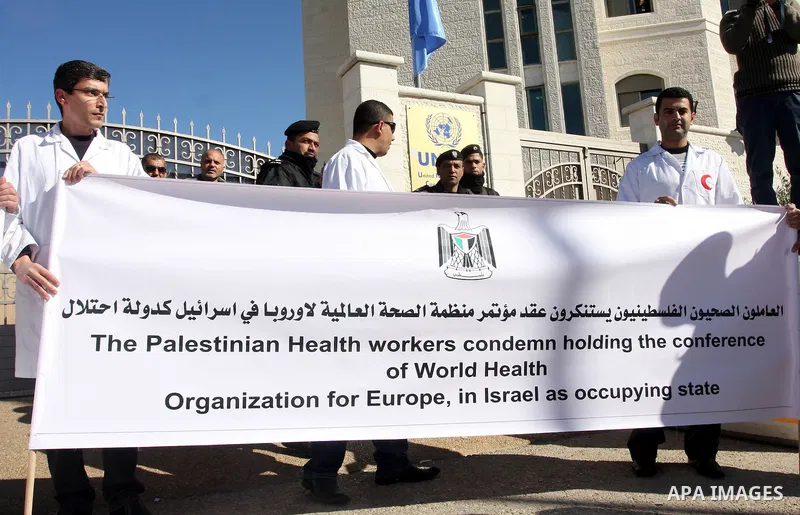 Palestinian doctors hold posters during a protest in front of UN headquarters in Ramallah, West Bank, November 28, 2011 to condemn holding the conference of World Health Organization for Europe, in Israel as the occupyin...