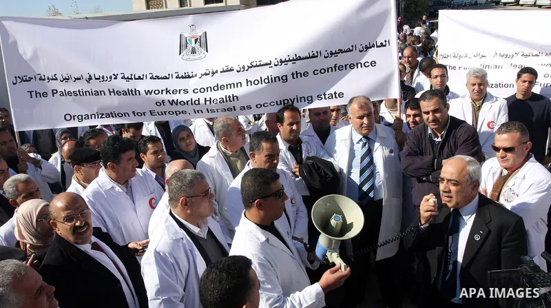Palestinian doctors hold posters during a protest in front of UN headquarters in Ramallah, West Bank, November 28, 2011 to condemn holding the conference of World Health Organization for Europe, in Israel as the occupyin...