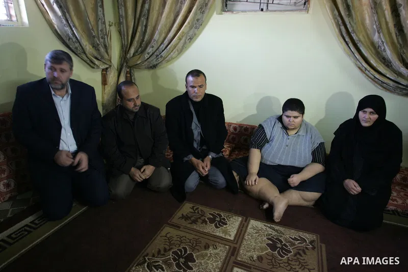Palestinian Ahmad Salama al-Najjar,21, sits with a delegation from the government at his family house in the southern Gaza Strip town of Khan Younis on Nov. 28,2011. Al-Najjar suffers from abnormal fatness since five yea...