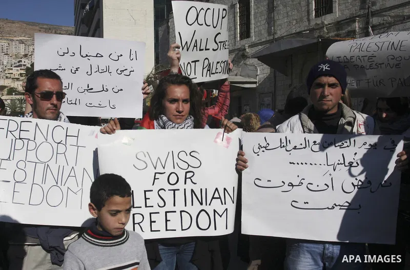 Palestinian and foreign peace activists hold placards during a gathering to mark the International Day of Solidarity with the Palestinian People, on November 29, 2011 in the West Bank city of Nablus. Photo by Wagdi Eshta...