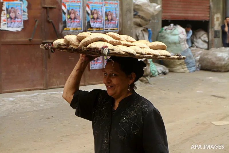 An Egyptian woman carries a tray of traditional bread on her head in Cairo, Egypt, on November 29, 2011. Egypt hailed the start of its first post-revolution election as a triumph for democracy as more voters headed to th...