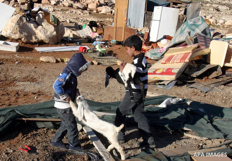 Palestinian Bedouin children collect belongings amidst the rubble of a structure after it was razed by the Israeli army in the West Bank village of Zayem, near Jerusalem November 29, 2011. According to Israeli authoritie...