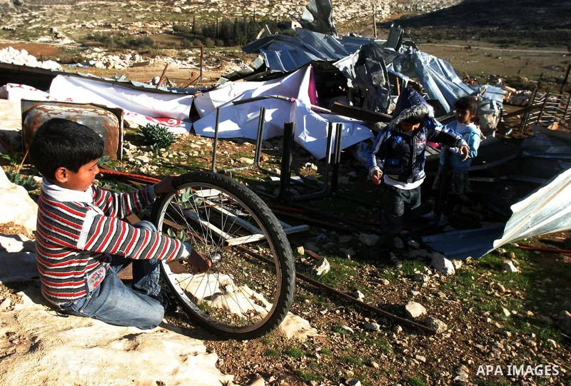 Palestinian Bedouin children collect belongings amidst the rubble of a structure after it was razed by the Israeli army in the West Bank village of Zayem, near Jerusalem November 29, 2011. According to Israeli authoritie...