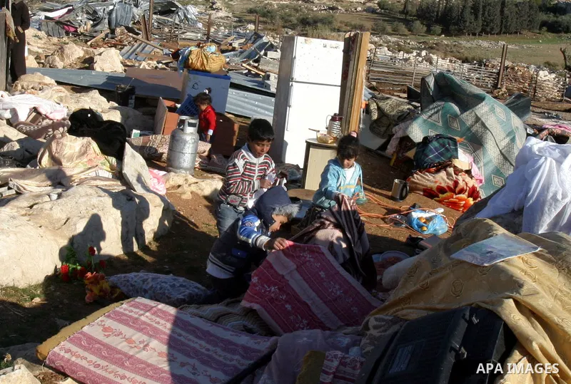 Palestinian Bedouin children collect belongings amidst the rubble of a structure after it was razed by the Israeli army in the West Bank village of Zayem, near Jerusalem November 29, 2011. According to Israeli authoritie...