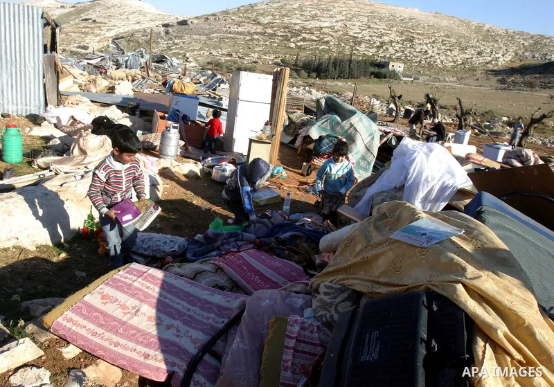 Palestinian Bedouin children collect belongings amidst the rubble of a structure after it was razed by the Israeli army in the West Bank village of Zayem, near Jerusalem November 29, 2011. According to Israeli authoritie...