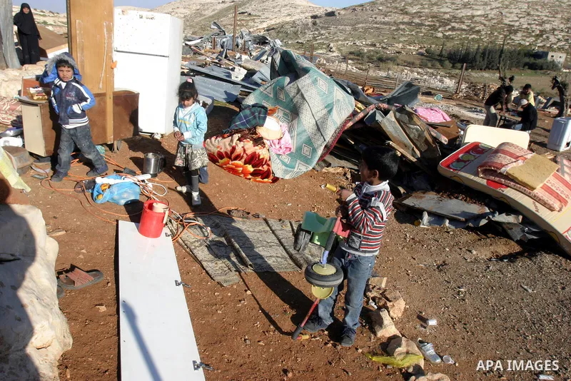 Palestinian Bedouin children collect belongings amidst the rubble of a structure after it was razed by the Israeli army in the West Bank village of Zayem, near Jerusalem November 29, 2011. According to Israeli authoritie...