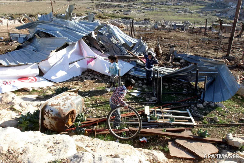 Palestinian Bedouin children collect belongings amidst the rubble of a structure after it was razed by the Israeli army in the West Bank village of Zayem, near Jerusalem November 29, 2011. According to Israeli authoritie...