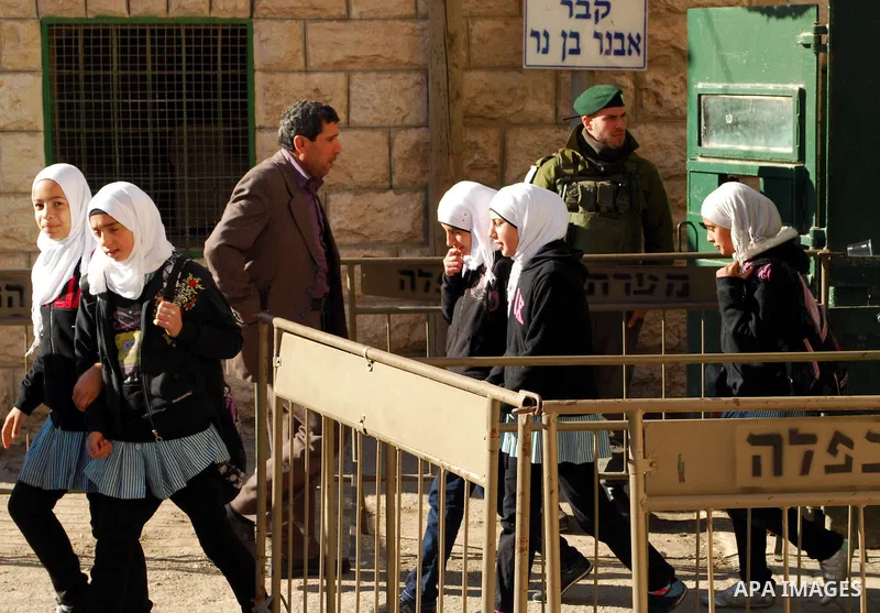 Palestinian schoolgirls walk past an Israeli checkpoint during their visit to the Ibrahimi mosque or the "Tomb of Patriarch" in the old city of Hebron on Dec. 1,2011. Photo by Osama Qawasmi