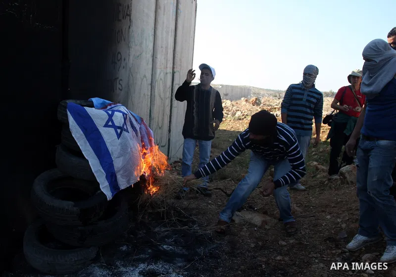 Palestinian protestors set fire the US and Israeli flags during a weekly demonstration near Israel's separation wall in the West Bank village of Nilin, on December 02, 2011. Photo by Issam Rimawi