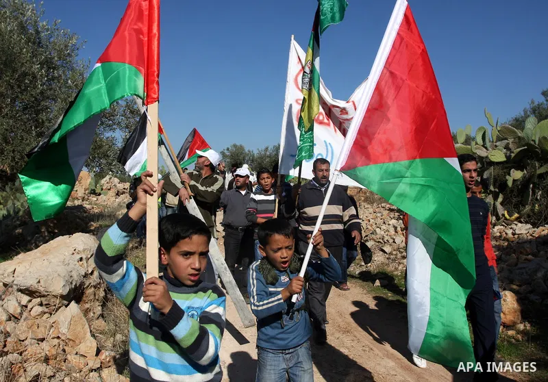 Palestinian protestors clash with Israeli forces standing on the other side of Israel's separation wall during a weekly protest in the West Bank village of Nilin, on December 02, 2011. Photo by Issam Rimawi