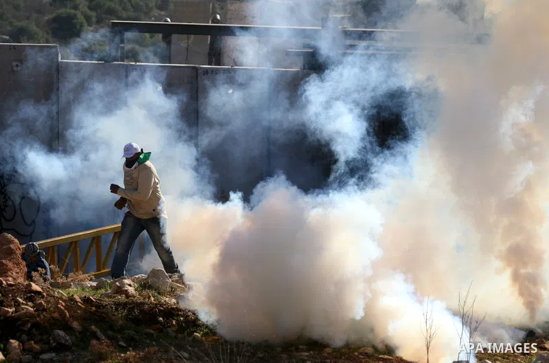 Palestinian protestors clash with Israeli forces standing on the other side of Israel's separation wall during a weekly protest in the West Bank village of Nilin, on December 02, 2011. Photo by Issam Rimawi
