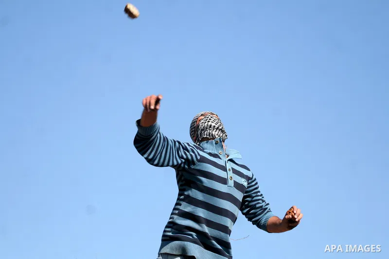 Palestinian protestors clash with Israeli forces standing on the other side of Israel's separation wall during a weekly protest in the West Bank village of Nilin, on December 02, 2011. Photo by Issam Rimawi