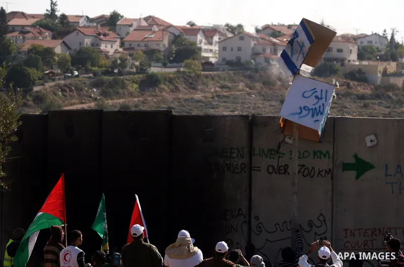Palestinian protestors clash with Israeli forces standing on the other side of Israel's separation wall during a weekly protest in the West Bank village of Nilin, on December 02, 2011. Photo by Issam Rimawi