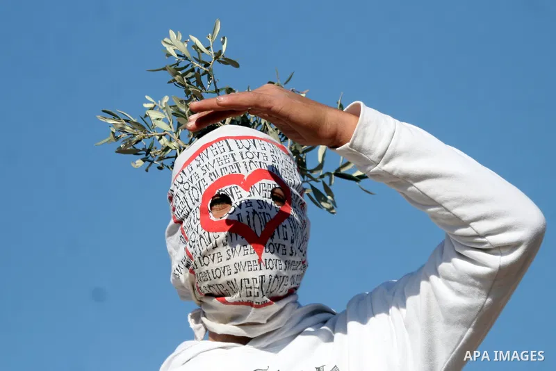 Palestinian protestors clash with Israeli forces standing on the other side of Israel's separation wall during a weekly protest in the West Bank village of Nilin, on December 02, 2011. Photo by Issam Rimawi