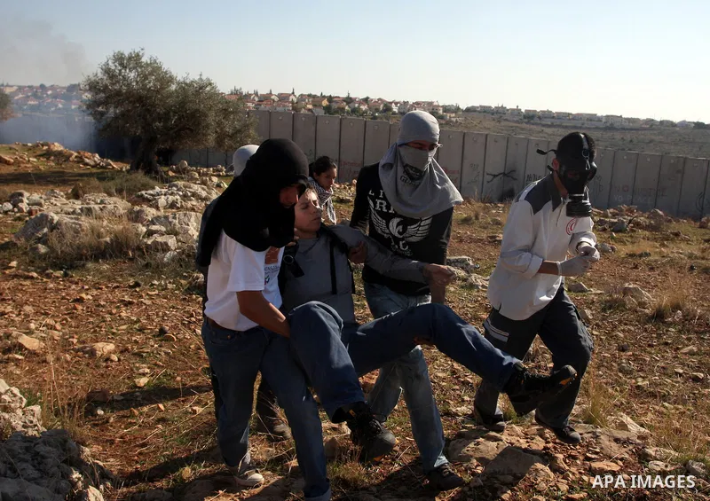 Palestinian protestors clash with Israeli forces standing on the other side of Israel's separation wall during a weekly protest in the West Bank village of Nilin, on December 02, 2011. Photo by Issam Rimawi