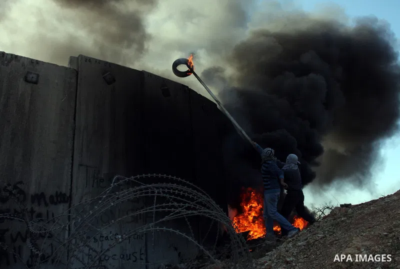 Palestinian protestors clash with Israeli forces standing on the other side of Israel's separation wall during a weekly protest in the West Bank village of Nilin, on December 02, 2011. Photo by Issam Rimawi