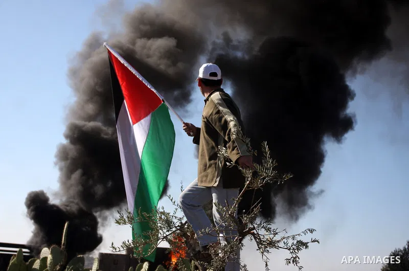 Palestinian protestors clash with Israeli forces standing on the other side of Israel's separation wall during a weekly protest in the West Bank village of Nilin, on December 02, 2011. Photo by Issam Rimawi