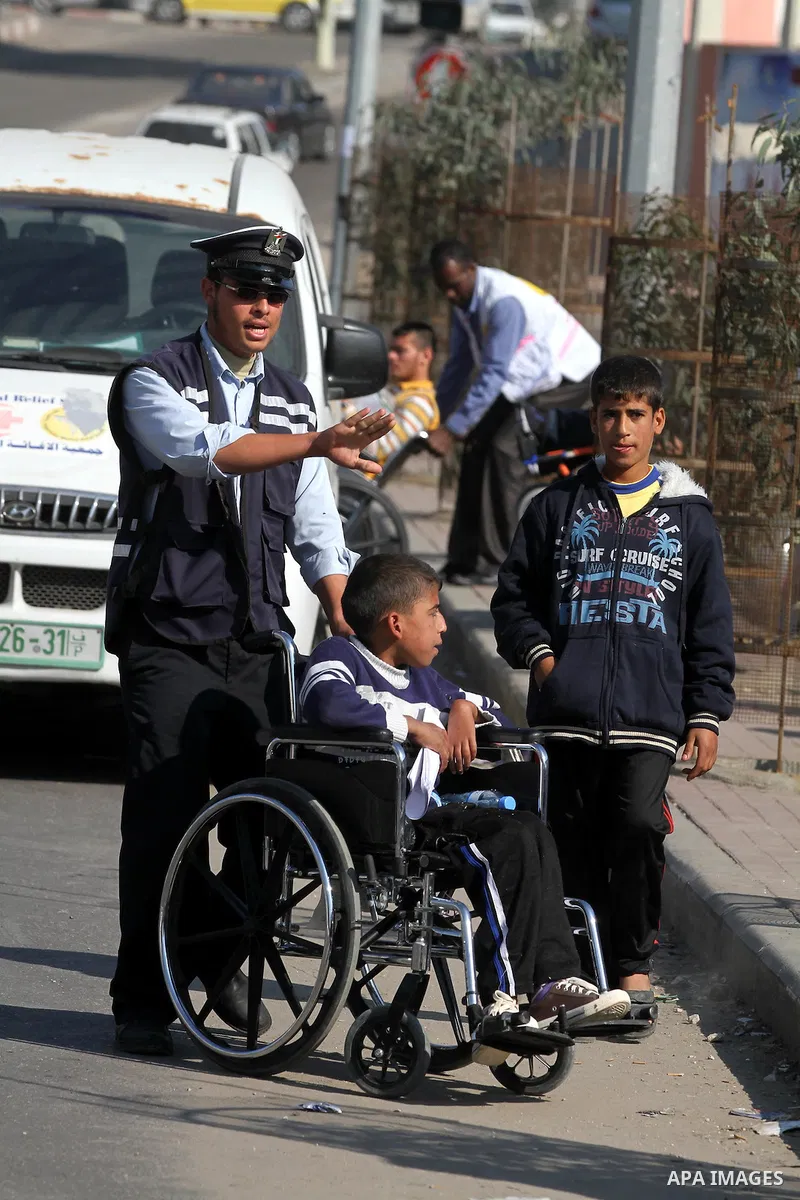 Palestinian policemen help a wheelchair-bound boy to cross a street in Gaza City during a gathering of people with special needs to mark the International Day for Persons with Disabilities on Dec. 03, 2011. Photo by Majd...