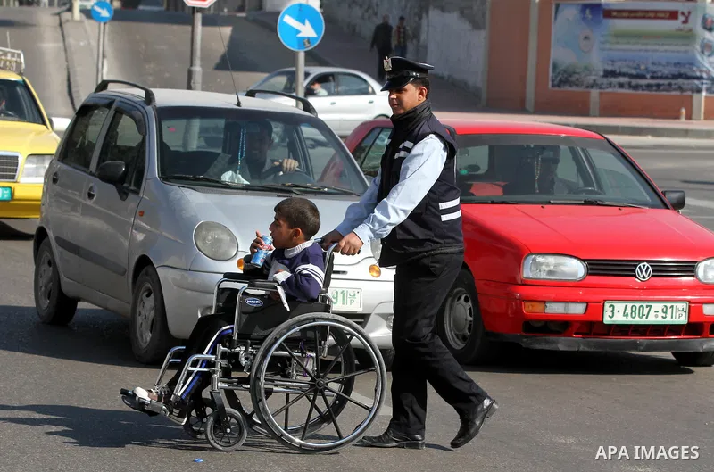 Palestinian policemen help a wheelchair-bound boy to cross a street in Gaza City during a gathering of people with special needs to mark the International Day for Persons with Disabilities on Dec. 03, 2011. Photo by Majd...