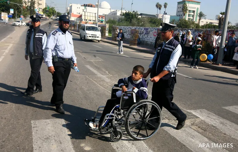 Palestinian policemen help a wheelchair-bound boy to cross a street in Gaza City during a gathering of people with special needs to mark the International Day for Persons with Disabilities on Dec. 03, 2011. Photo by Majd...