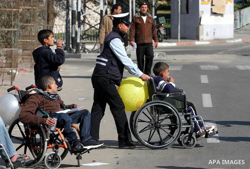 Palestinian policemen help a wheelchair-bound boy to cross a street in Gaza City during a gathering of people with special needs to mark the International Day for Persons with Disabilities on Dec. 03, 2011. Photo by Majd...