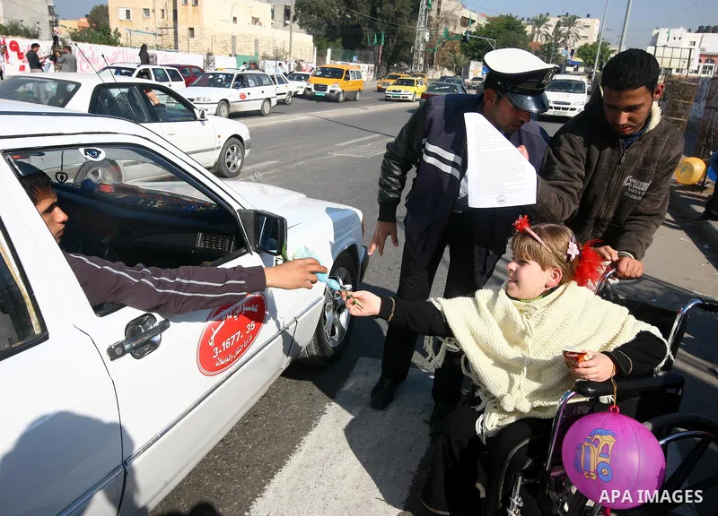 Palestinian policemen help a wheelchair-bound girl to cross a street in Gaza City during a gathering of people with special needs to mark the International Day for Persons with Disabilities on Dec. 03, 2011. Photo by Maj...