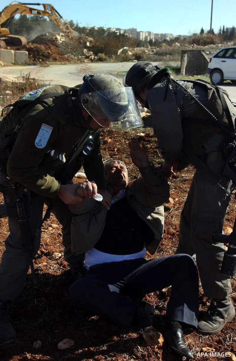 A Palestinian man is carried by Israeli border police officers after he tried to block a construction vehicle from working on Israel's barrier in the West Bank village of Qaladiya near Ramallah December 4, 2011. Accordin...