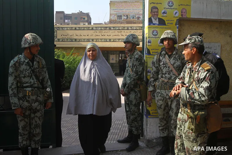 A woman enters a polling station guarded by soldiers and police during the first round of Egypt's run-off parliamentary elections in Cairo December 5, 2011. Egyptians voted on Monday in run-off contests for parliamentary...