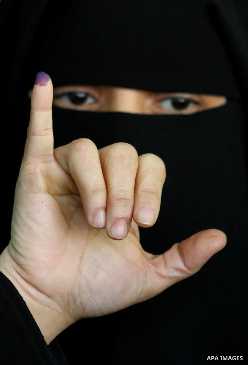 An Egyptian woman shows her ink-stained finger during the run-off of the first round of parliamentary voting in the Cairo neighbourhood of al-Manial on December 5, 2011. Islamist candidates in Egypt looked to extend thei...
