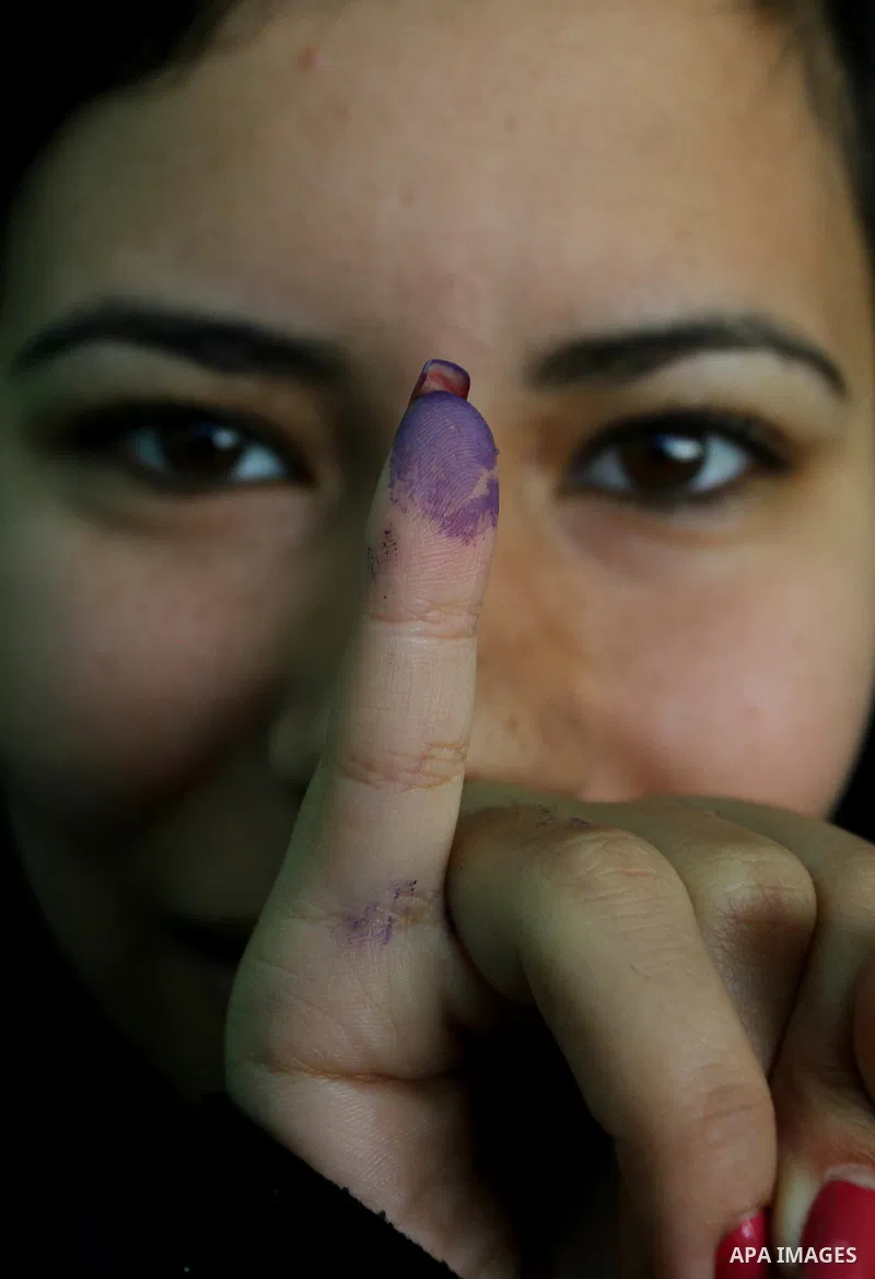 An Egyptian woman shows her ink-stained finger during the run-off of the first round of parliamentary voting in the Cairo neighbourhood of al-Manial on December 5, 2011. Islamist candidates in Egypt looked to extend thei...