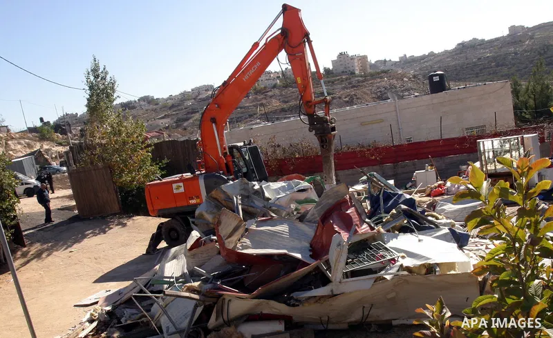 Israeli forces stand guard as a bulldozer destroy a Palestinian family house in an area of the east Jerusalem neighborhood of Beit Hanina which falls in the West Bank side of Israel's separation barrier on Dec. 5, 2011....
