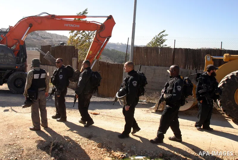 Israeli forces stand guard as a bulldozer destroy a Palestinian family house in an area of the east Jerusalem neighborhood of Beit Hanina which falls in the West Bank side of Israel's separation barrier on Dec. 5, 2011....