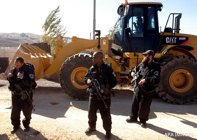 Israeli forces stand guard as a bulldozer destroy a Palestinian family house in an area of the east Jerusalem neighborhood of Beit Hanina which falls in the West Bank side of Israel's separation barrier on Dec. 5, 2011....