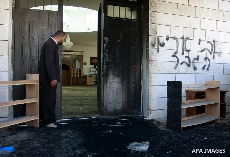Palestinians stand outside a vandalized mosque where graffiti reading In Hebrew. was sprayed at the entrance of the mosque , in the West Bank Village of Brukin near Nablus, Wednesday , Dec. 07, 2011. Assailants vandalize...