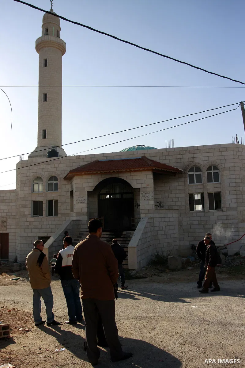 Palestinians stand outside a vandalized mosque where graffiti reading In Hebrew. was sprayed at the entrance of the mosque , in the West Bank Village of Brukin near Nablus, Wednesday , Dec. 07, 2011. Assailants vandalize...