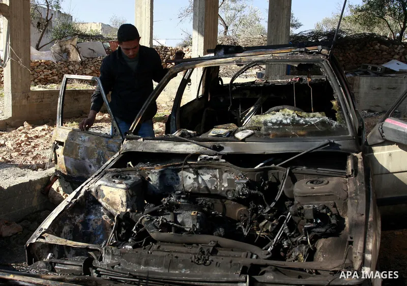 A Palestinian man stands next a burning vehicle which residents said was torched by Jewish settlers in the West Bank Village of Brukin near Nablus, Wednesday , Dec. 07, 2011. Assailants vandalized a Palestinian mosque ea...