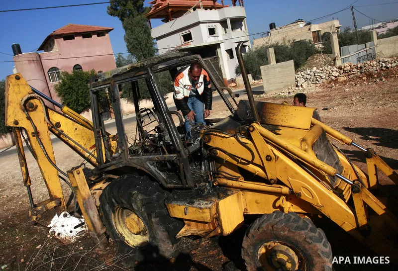 A Palestinian man stands on a burning vehicle which residents said was torched by Jewish settlers in the West Bank Village of Brukin near Nablus, Wednesday , Dec. 07, 2011. Assailants vandalized a Palestinian mosque earl...