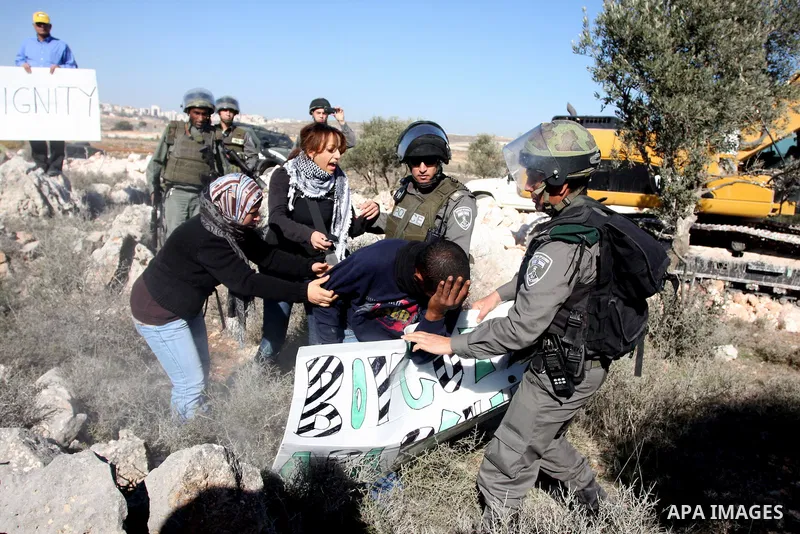 Israeli border police officers scuffle with protesters after they tried to block a construction vehicle from working on Israel's barrier in the West Bank village of Qalandiya near Ramallah December 7, 2011. According to...