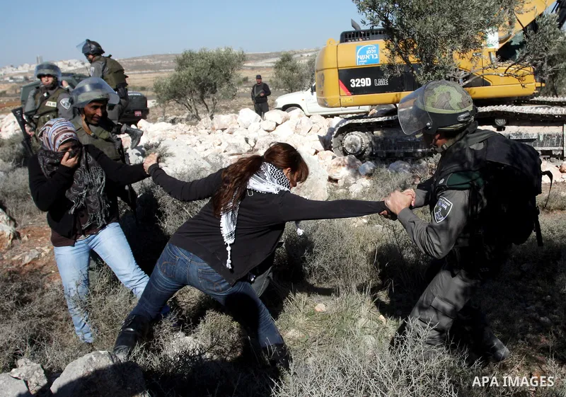 Israeli border police officers scuffle with protesters after they tried to block a construction vehicle from working on Israel's barrier in the West Bank village of Qalandiya near Ramallah December 7, 2011. According to...