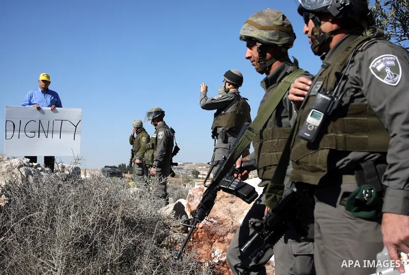 Israeli border police officers scuffle with protesters after they tried to block a construction vehicle from working on Israel's barrier in the West Bank village of Qalandiya near Ramallah December 7, 2011. According to...