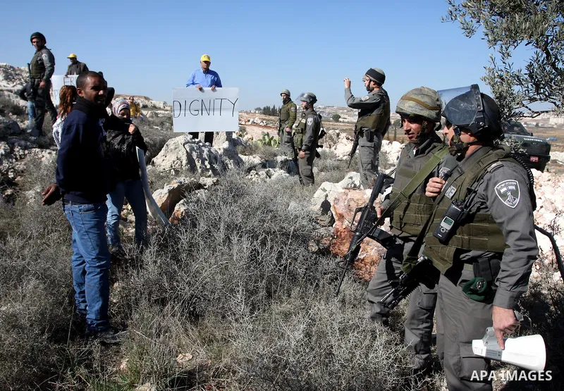 Israeli border police officers scuffle with protesters after they tried to block a construction vehicle from working on Israel's barrier in the West Bank village of Qalandiya near Ramallah December 7, 2011. According to...