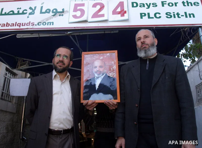 Palestinian Hamas lawmakers Mohammed Totah and Khaled Abu Arafa hold a picture for Hamas lawmaker Ahmed Abu Attoun at Red Cross headquarters in east Jerusalem on Dec. 6,2011. Israel has expelled a Hamas lawmaker who was...