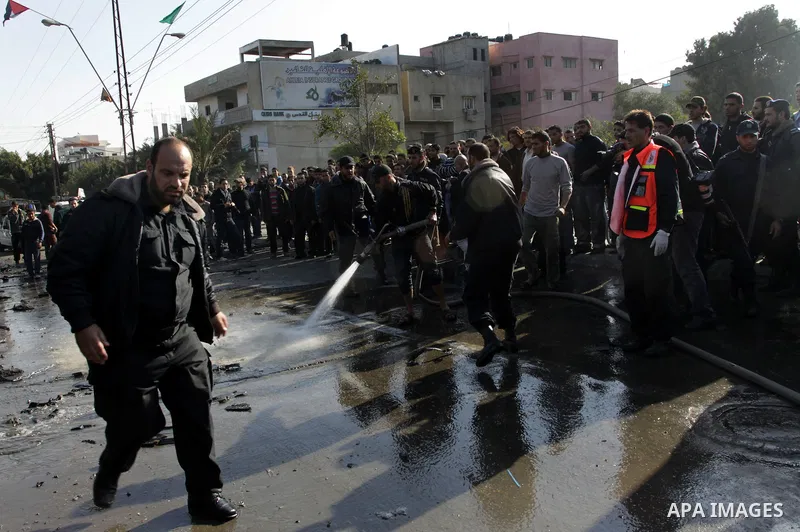 Palestinians crowd around the remains of a car hit by an Israeli air strike in Gaza City December 8, 2011. An Israeli air strike on the car killed at least two Hamas militants and wounded two others on a crowded Gaza str...