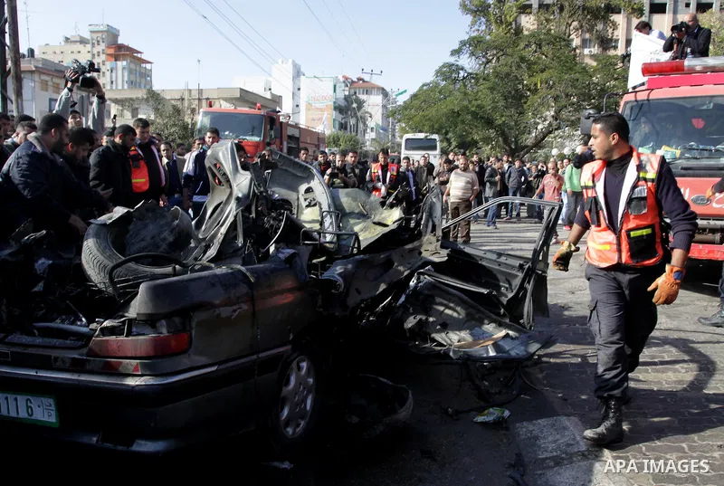 Palestinians crowd around the remains of a car hit by an Israeli air strike in Gaza City December 8, 2011. An Israeli air strike on the car killed at least two Hamas militants and wounded two others on a crowded Gaza str...